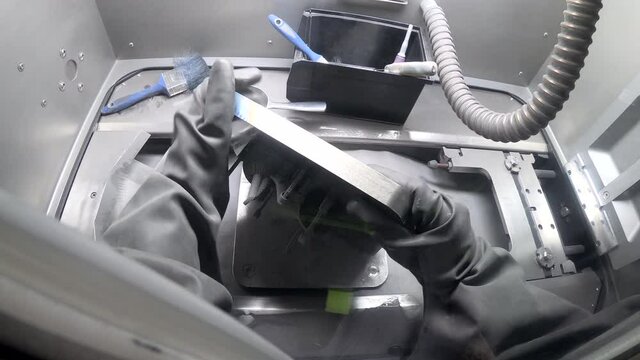 Worker in isolated rubber gloves turns platform with printed models and cleaning