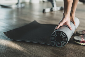 Young woman preparing material for practice yoga and meditating indoors at the gym. She likes to exercise by doing yoga in the morning because it makes her feel relaxed and calm before going to work.