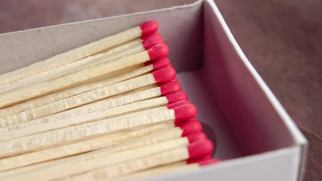 Full open box of matches with red sulfur heads on wooden background. Macro. Rotation. To light the fire