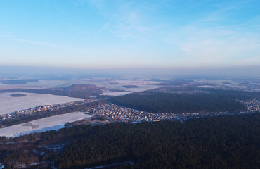 Aerial view of winter snowy landscape with forest and field
