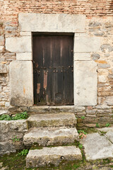 Fototapeta na wymiar Stone wall with old entrance and wooden door