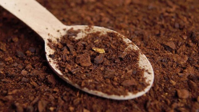 Roasted chicory root powder in wooden teaspoon. Brown instant herbal granules. Macro. Rotation