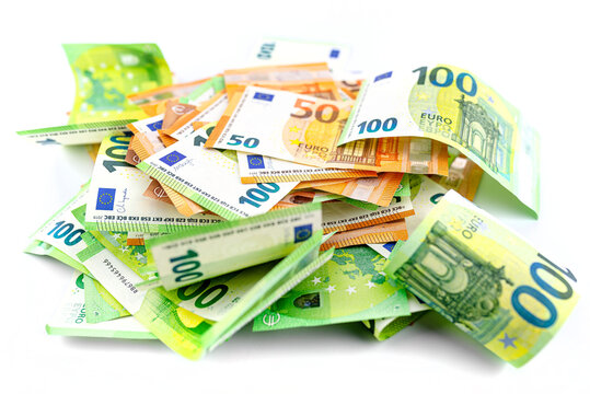 Macro photo of European Union currency, scattered on pile of 50 and 100 euro banknotes, isolated on a white background.