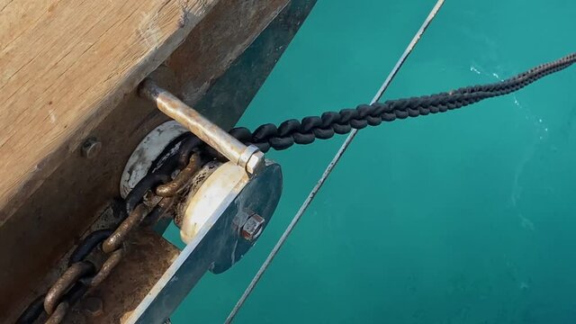 sliding of the anchor chain along the tension roller on the bow of the yacht while dropping the anchor