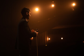 WIDE young aspiring musician playing violin on a stage of a large venue. Shot with 2x anamorphic...