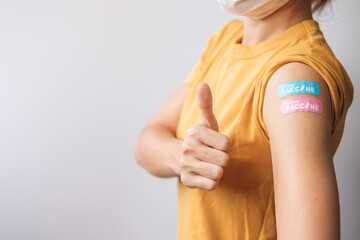 woman showing Thumb sign with bandage after receiving covid 19 vaccine. Vaccination, herd immunity,...