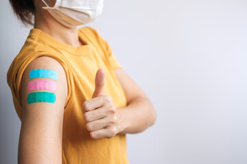 woman showing Thumb sign with bandage after receiving covid 19 vaccine. Vaccination, herd immunity, side effect, booster dose, vaccine passport and Coronavirus pandemic - obrazy, fototapety, plakaty