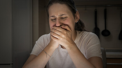 Portrait of stressed crying woman holding her scream with hands