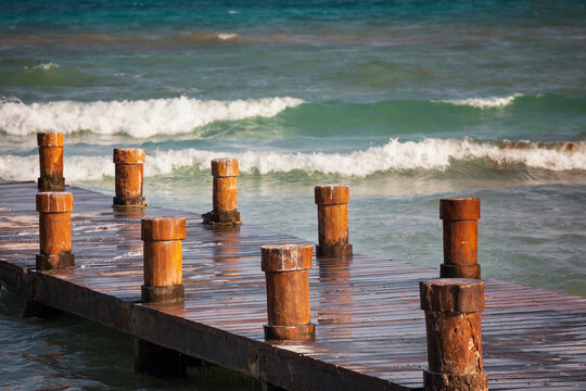 Fototapeta A wooden pier with posts or bollards on the coastline