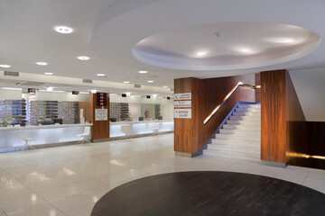 Waiting area and reception desk at a modern hospital, with signs and electronic display