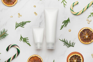 Obraz na płótnie Canvas Cosmetics tubes mockup, Christmas concept. Two blank white moisturizing cream tubes. Winter hand care products.