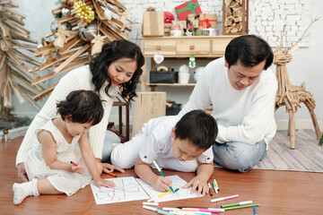 Parents and children drawing pictures to decorate house for Christmas celebration