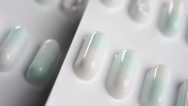 White blister packs with green pharmaceutical capsules. Pills group. Macro. Rotation. Virus medication concept