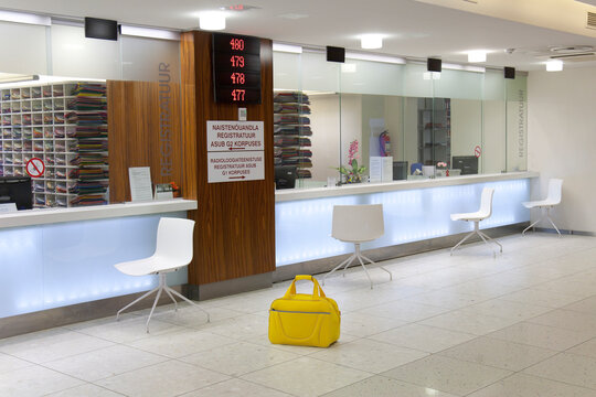 Waiting area and reception desk at a modern hospital, with signs and electronic display Yellow bag.