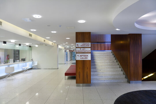 Waiting area and reception desk at a modern hospital, with signs and stairs