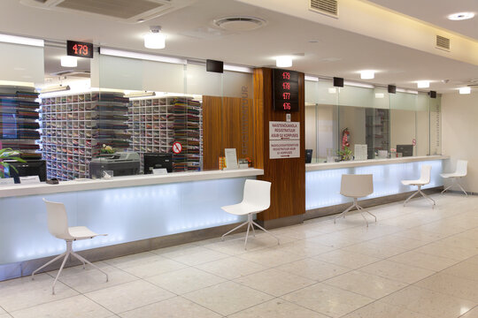 Waiting area and reception desk at a modern hospital, with signs and electronic display