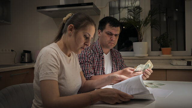 Stresed young family receiving bank debt notification and counting their money