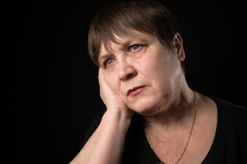 Grandmother with a serious look in a black T-shirt on a black background.