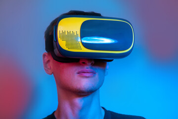 Portrait of young man in a VR helmet in neon colors