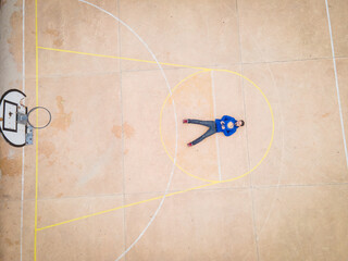 Aerial view of man seen laying on free throw line of basketball court