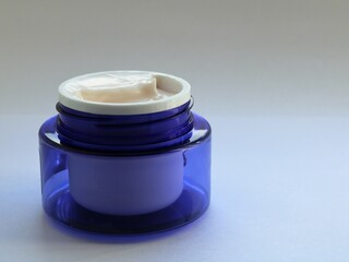 new open blue jar with gentle light skin cream on a white blank background, an example of skin care cosmetics for women isolated on a light backdrop, cream in a plastic jar