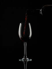
wine and champagne glass on black background with pouring red wine
