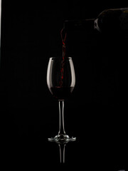 
wine and champagne glass on black background with pouring red wine