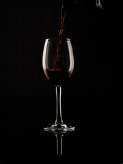 
wine and champagne glass on black background with pouring red wine