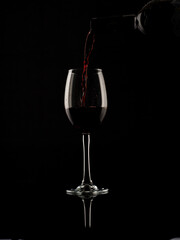 Naklejka na ściany i meble wine and champagne glass on black background with pouring red wine