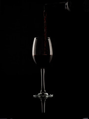 
wine and champagne glass on black background with pouring red wine
