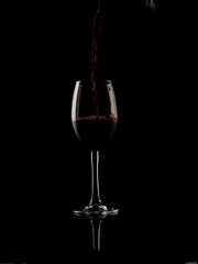 Naklejka na ściany i meble wine and champagne glass on black background with pouring red wine