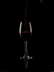 
wine and champagne glass on black background with pouring red wine