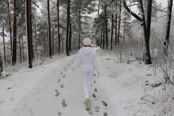 Young woman walking in a winter park. Person walking in the snow