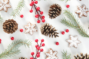 Christmas tree branches, conifer cones and red berries, holiday cookies and ornaments, top view on white background. Christmas, winter holiday, new year concept.	