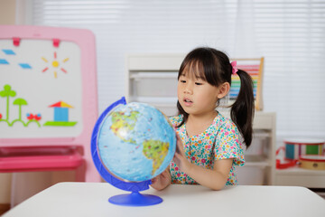 young girl learning world globe at home