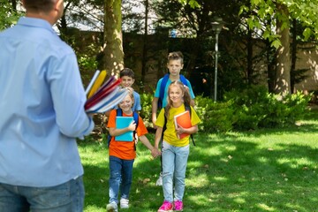 Schoolchildren greeting their teacher in natural park background