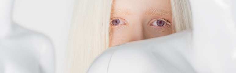 Blonde and albino woman looking at camera near mannequin isolated on white, banner.