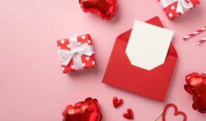 Top view photo of valentine's day decorations red envelope with card gift boxes in red wrapping paper with pattern of hearts and heart shaped balloons on isolated pastel pink background with copyspace
