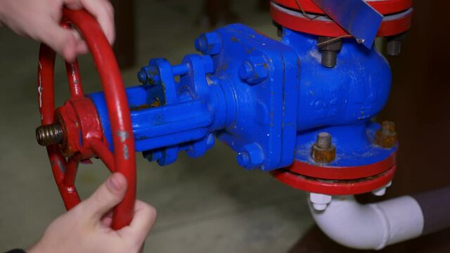 Close-up of unscrewing the valve of the tap for supplying liquid from the reservoir. Oil and gas industry and production. Work at an oil refinery. Opening the supply valve at the factory.