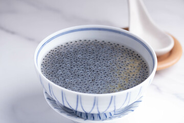 Basil seeds in sweet coconut milk in a white ceramic cup