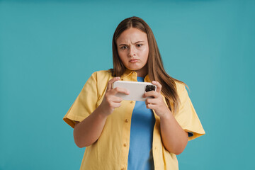 Young white woman frowning while playing online game on cellphone