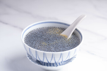 Basil seeds in sweet coconut milk in a white ceramic cup