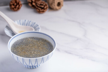 Basil seeds in sweet coconut milk in a white ceramic cup