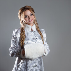 The Snow Maiden, a beautiful young woman in a fabulous fur coat of silver color, hands in a fur muff, a character in a winter Christmas or New Year fairy tale.