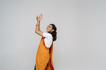 Young south asian woman wearing sari smiling while dancing at camera
