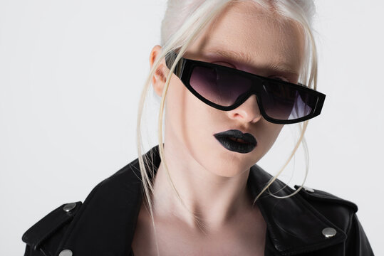 Fashionable albino woman in sunglasses and leather jacket isolated on white.