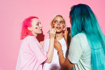 Young three women with multicolored hair making rainbow makeup