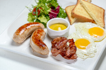 breakfast sausages with scrambled eggs toast and salad with sauce on a white plate on a white background macro photo
