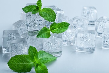 Top view of mint leaves with ice cubes and water drops on pastel background