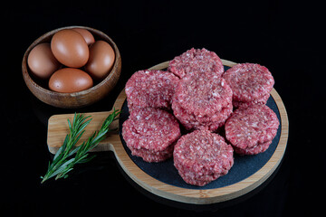 Raw beef meatballs made with various homemade spicy, beef kofta kofta raw, on black ground.